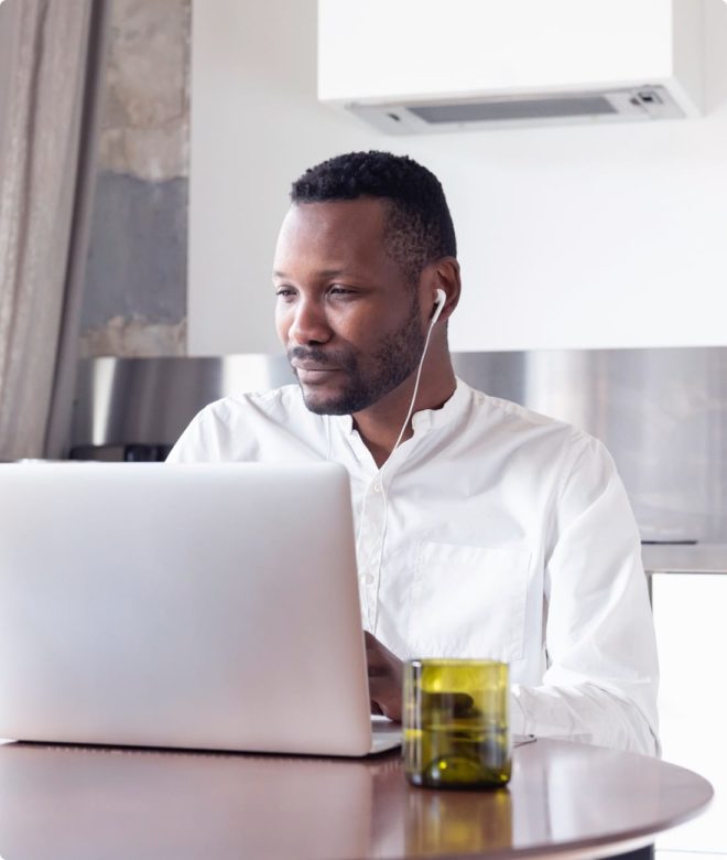 African American man smiling at the computer with headphones on