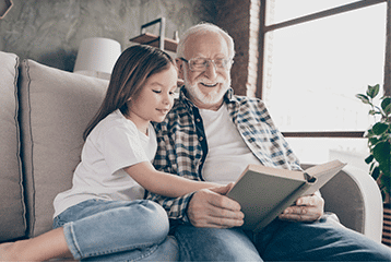 A grandfather and granddaughter in New York reading a book on hearing aids and hearing devices.