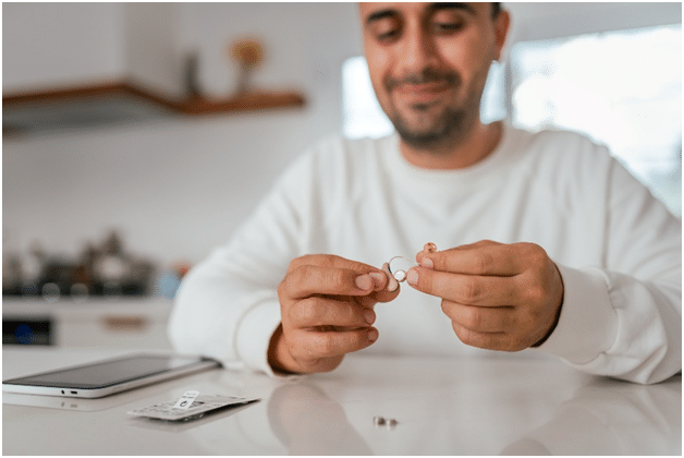 A New York resident replaces his old hearing aids at his kitchen table.